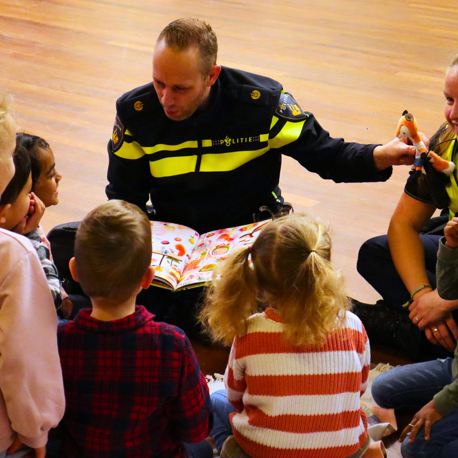 Twee agenten leest groep kinderen voor tijdens de voorleespicknick van 2025. 