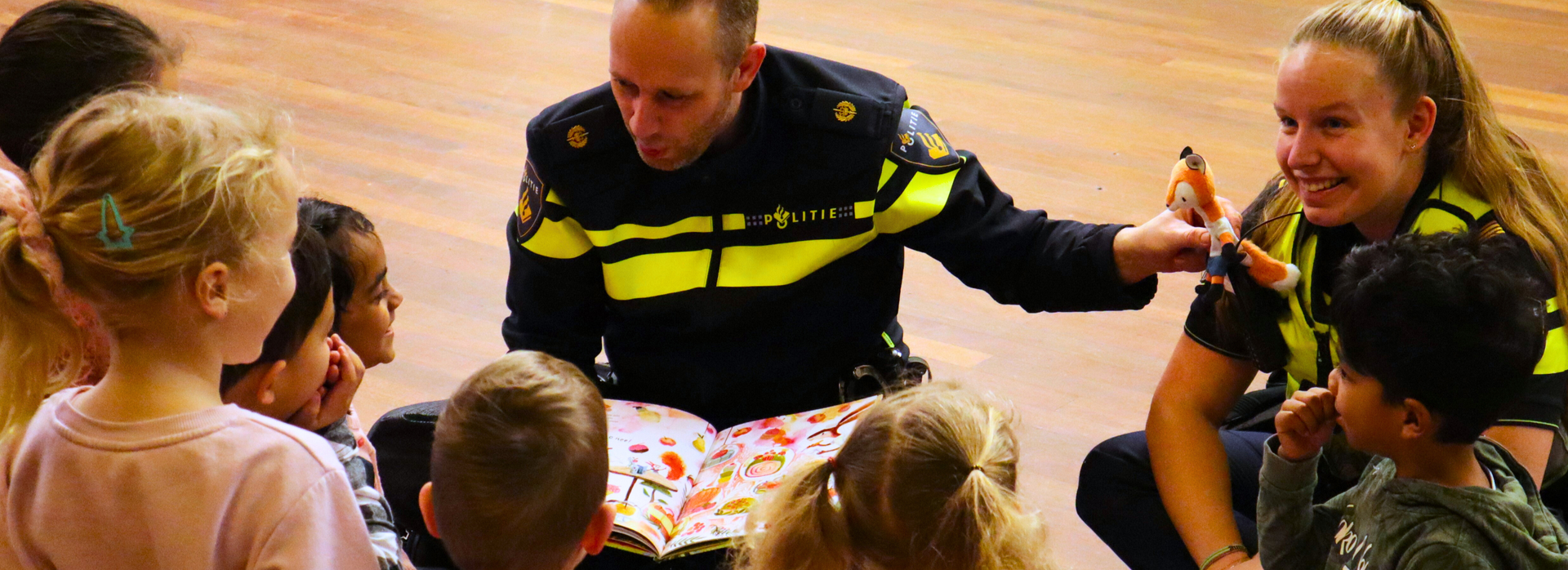 Twee agenten leest groep kinderen voor tijdens de voorleespicknick van 2025. 