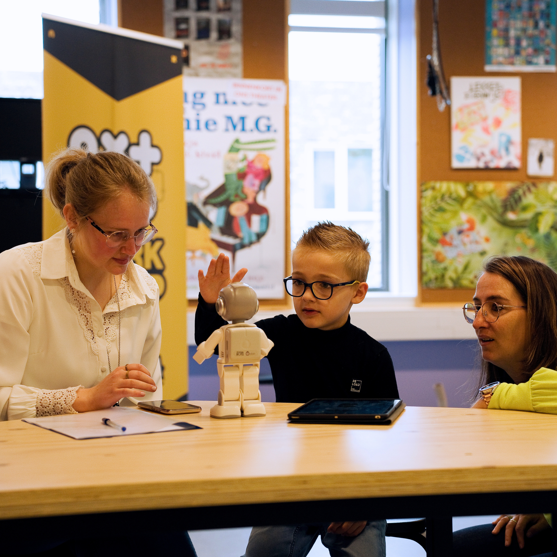 Kind met twee begeleiders in het NXT Lab bestuderen een robot.