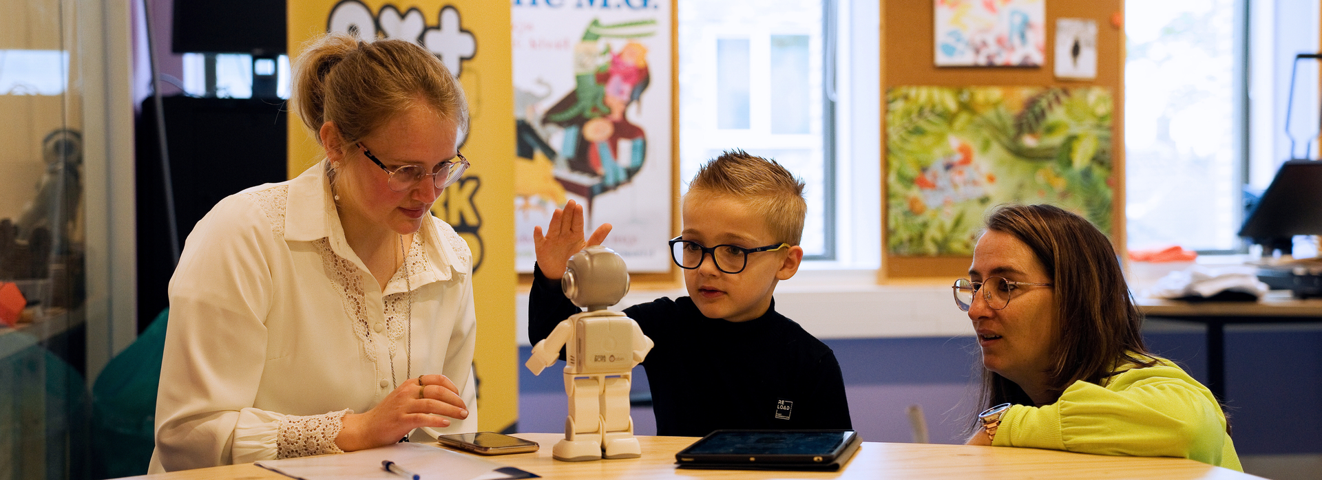 Kind met twee begeleiders in het NXT Lab bestuderen een robot.