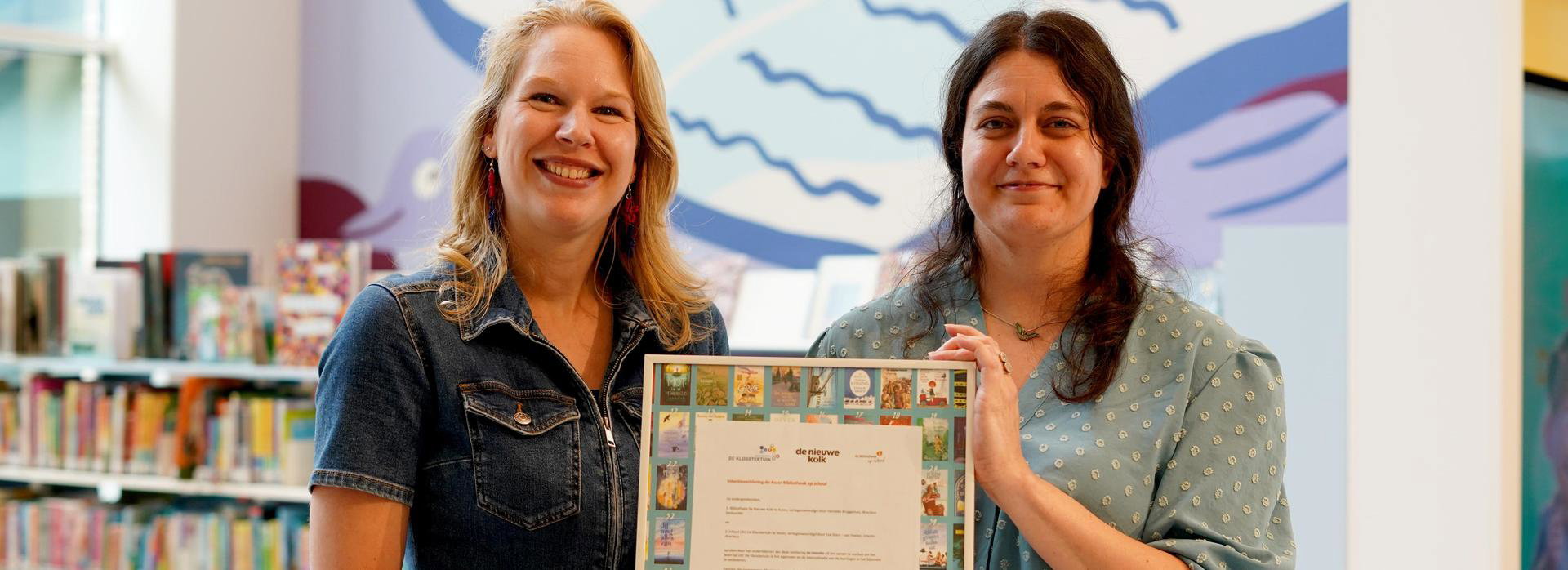 Docent van PO Kloostertuin en Leesmediaconsulent tekenen samenwerkingscontract.