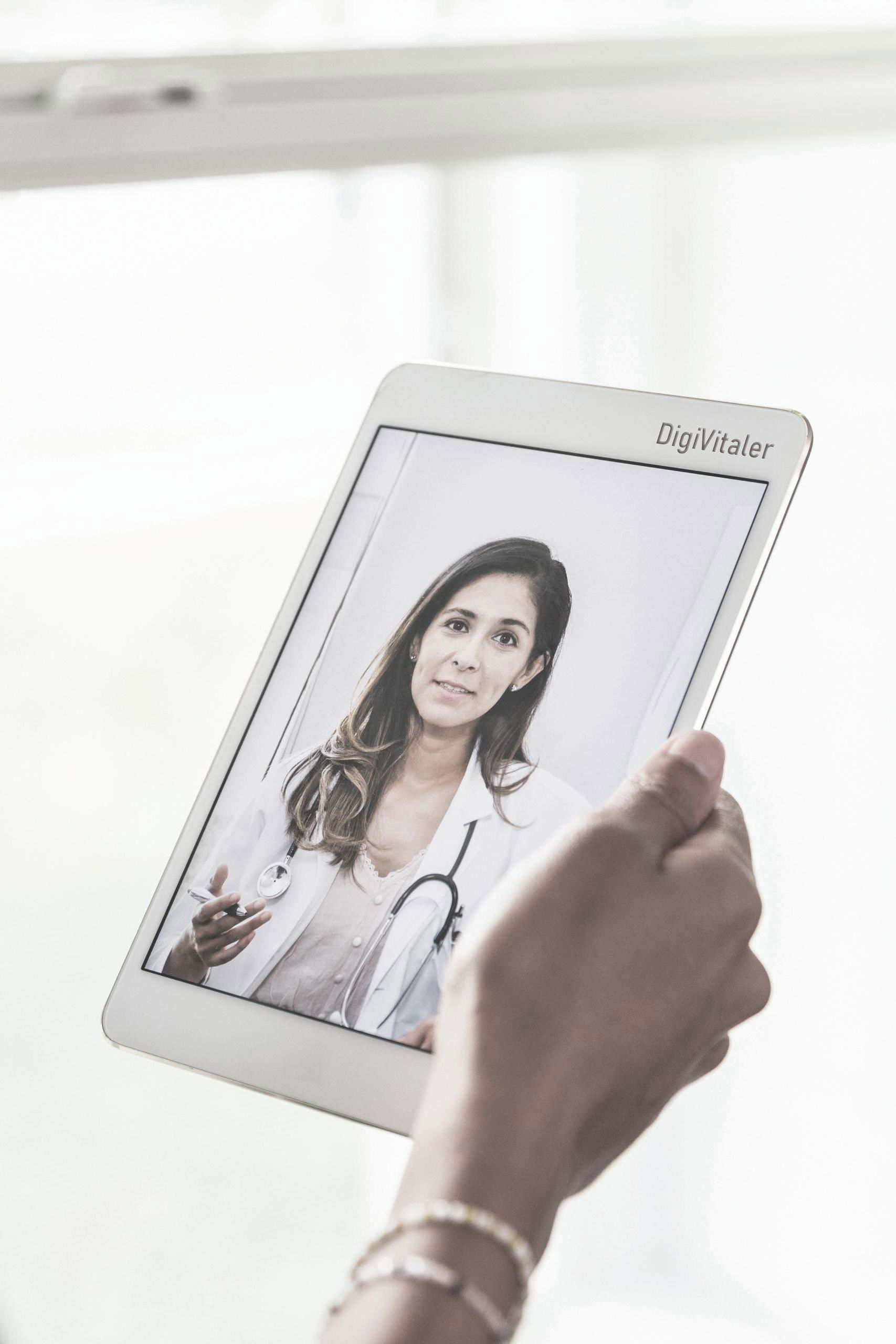 Persoon bekijkt op een tablet een video van een arts.