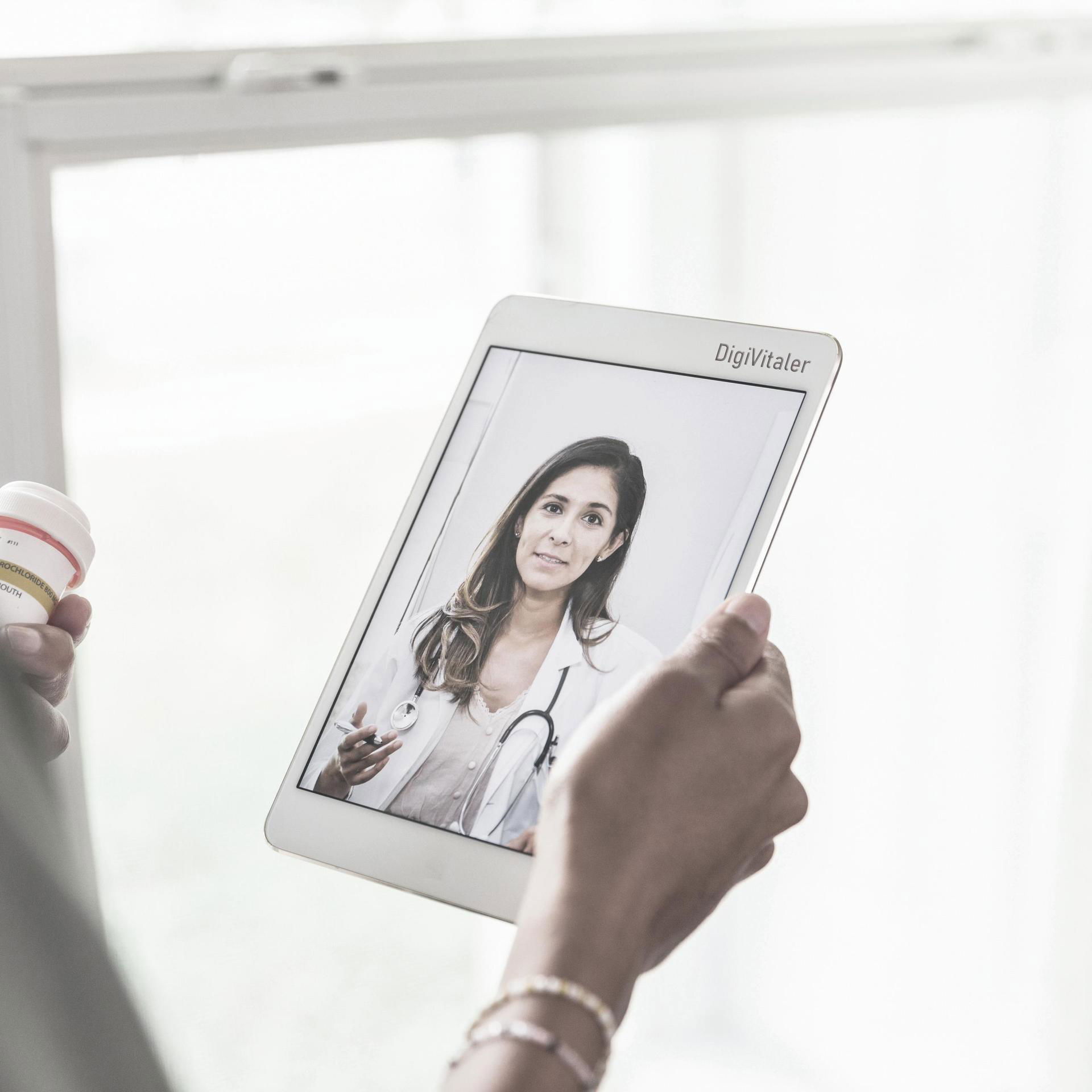 Persoon bekijkt op een tablet een video van een arts.