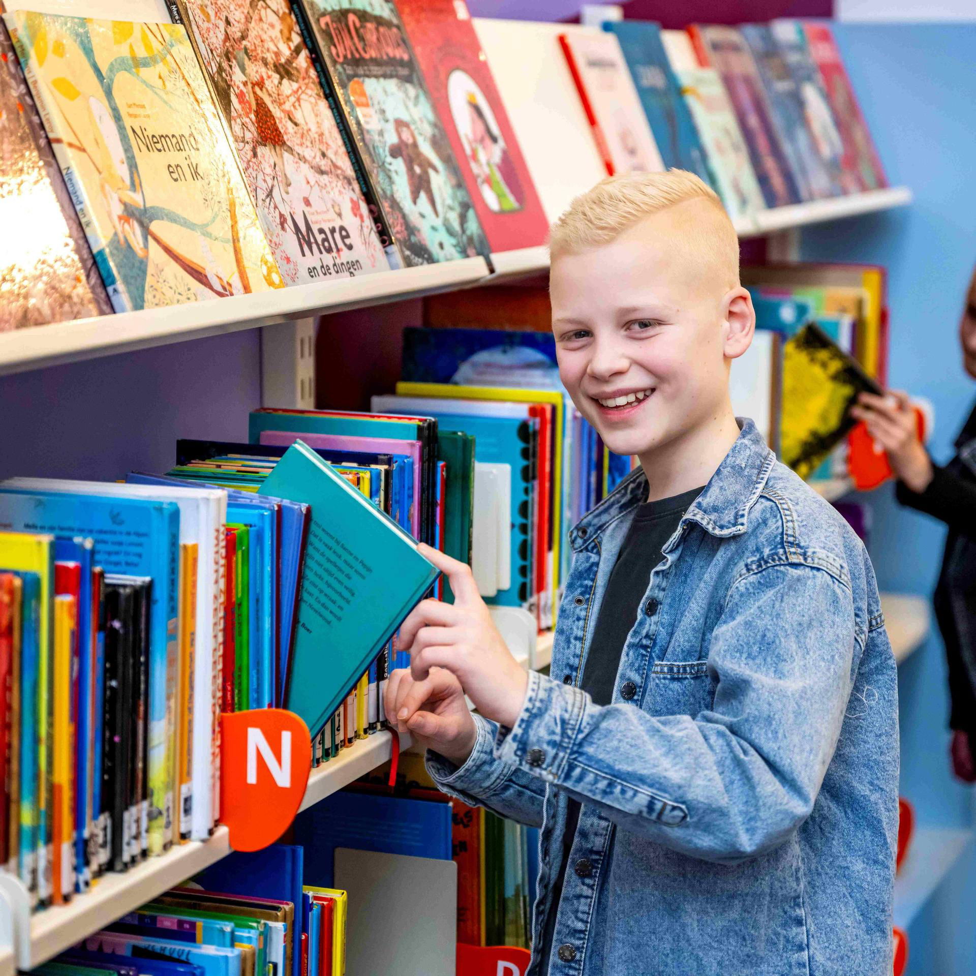 Jongen pakt een leesboek uit de boekenkast.