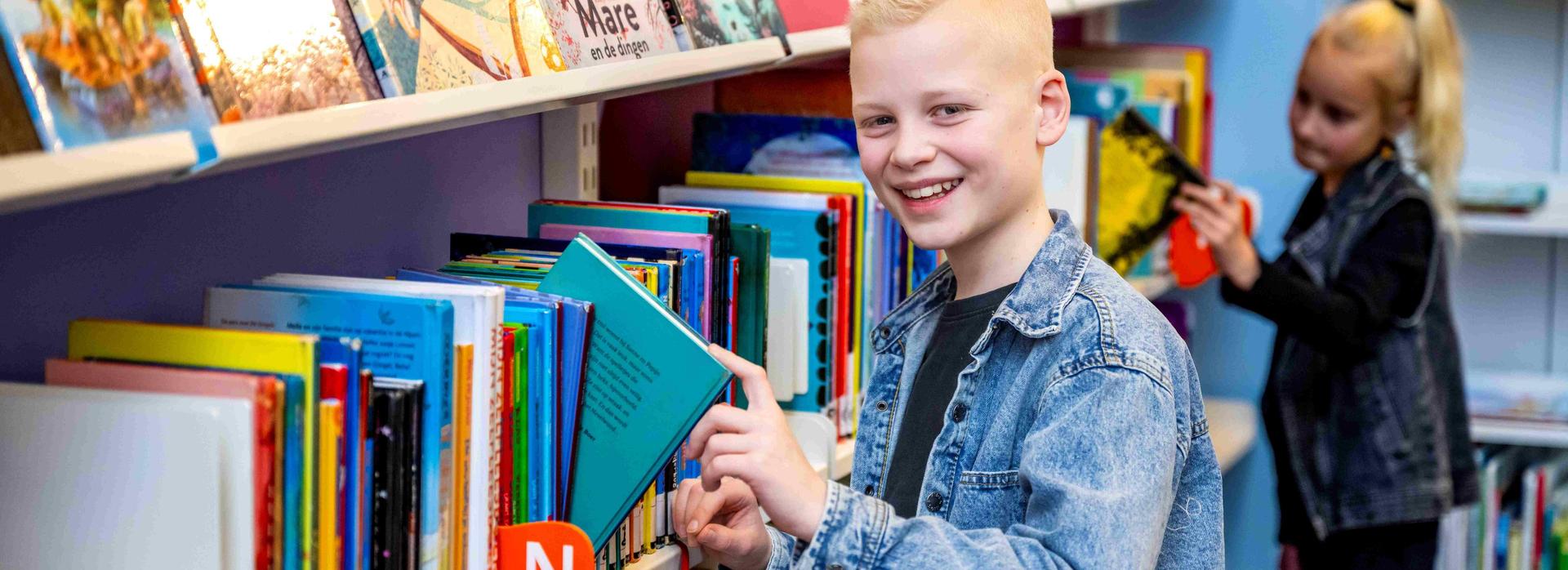 Jongen pakt een leesboek uit de boekenkast.