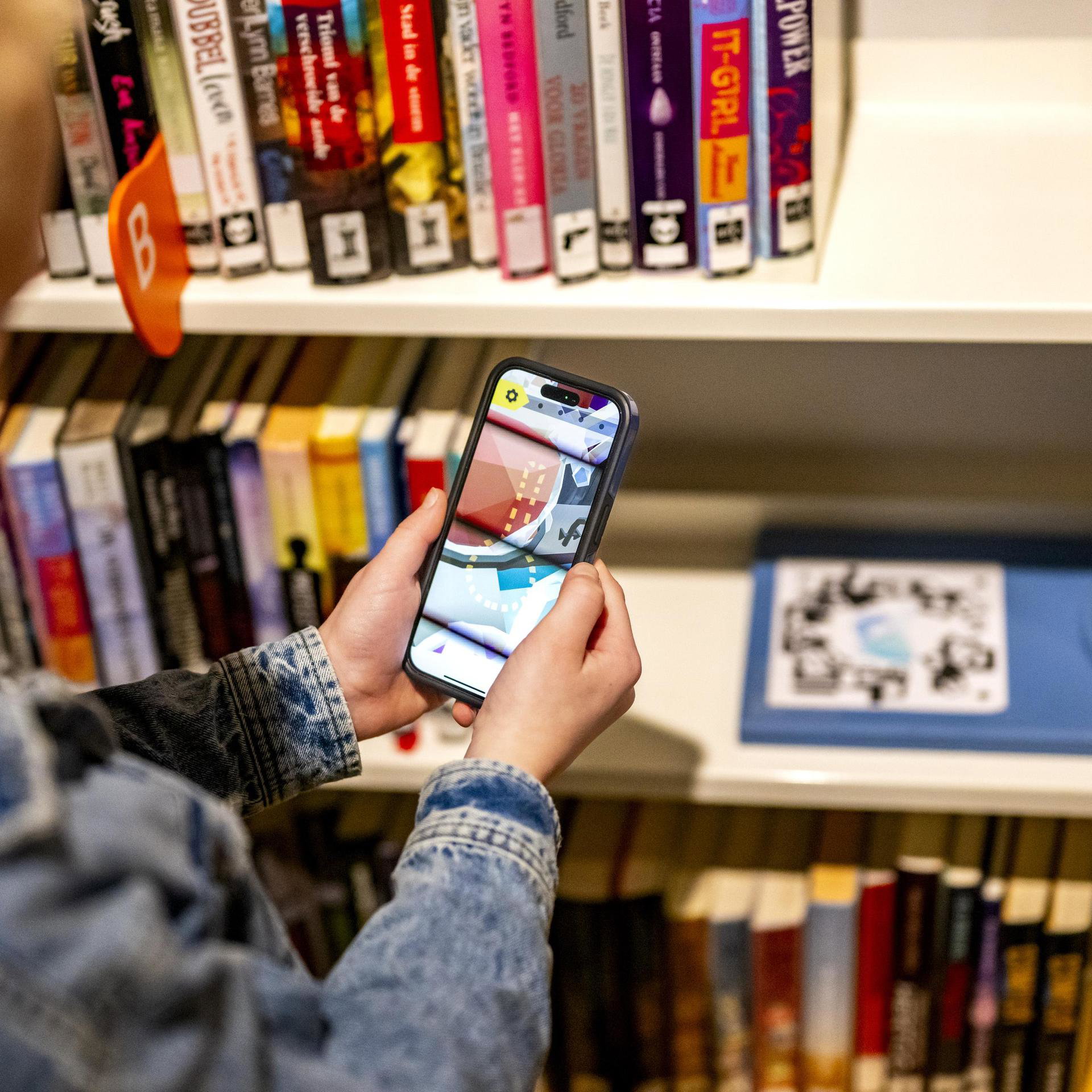 Close-up van kinderen die een smartphone in de bieb vasthouden.