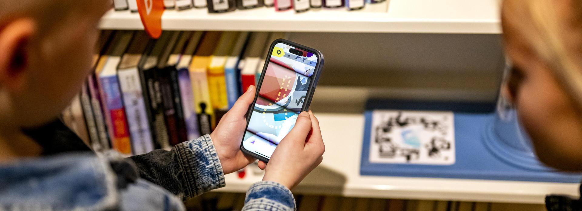Close-up van kinderen die een smartphone in de bieb vasthouden.