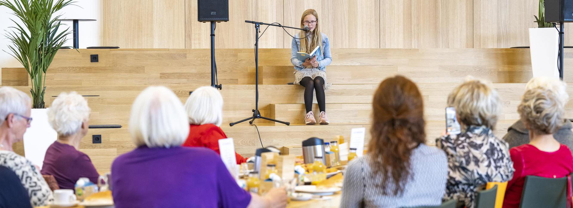 Ouderen worden tijdens lunch in De Nieuwe Kolk voorgelezen door meisje