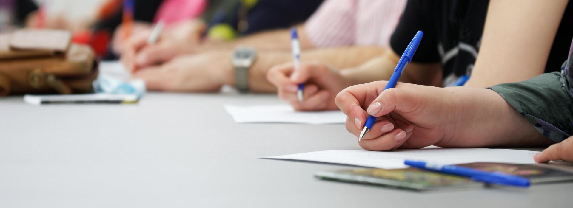 Close up van groep mensen die aan het schrijven zijn